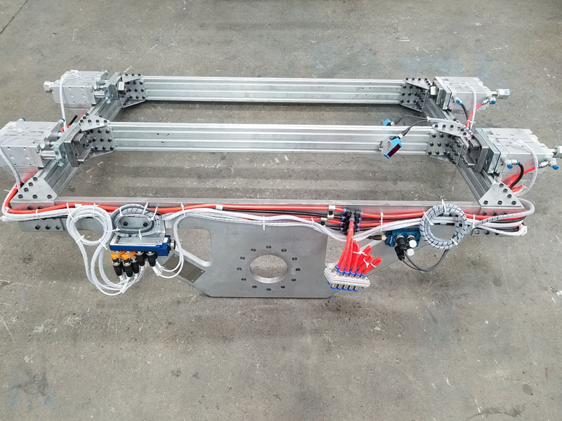 Metal industrial frame assembly with wiring and connectors lying on a concrete floor, gray and red tones, technical mood